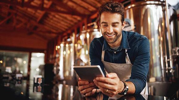 A male brewery worker looking at a tablet in a brewery
