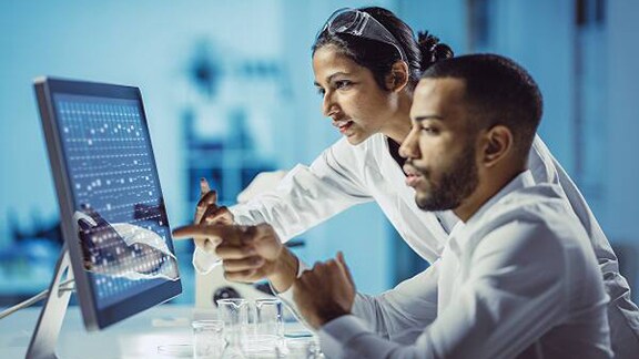 A male and female doctor examining data on a monitor