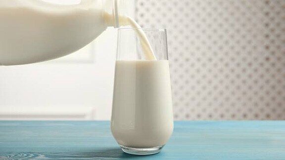 A can of milk being poured into a glass