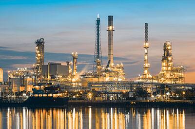 View of a sprawling oil refinery reflected on a body of water at dusk