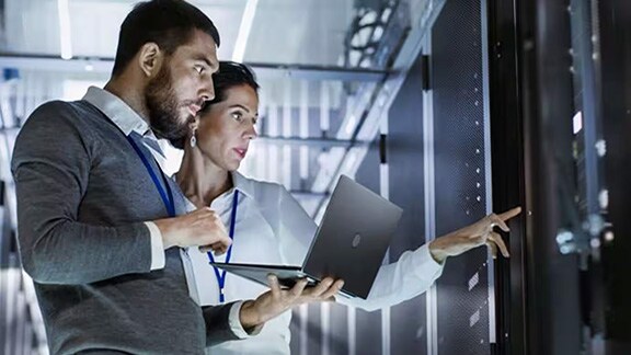 Man and woman working and conversing in a server room