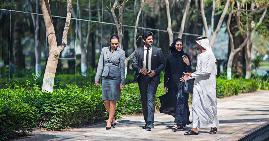 Four young professionals talking and strolling down a promenade
