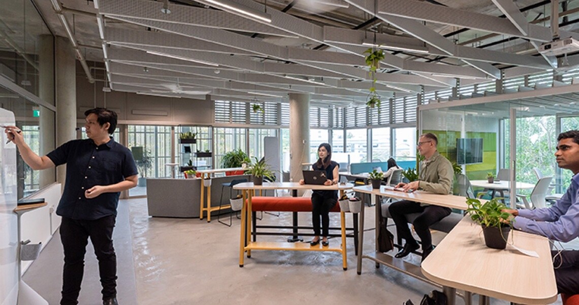 Three people attentively listening to a session being conducted by a man at the OpenBlue Innovation Center in Singapore
