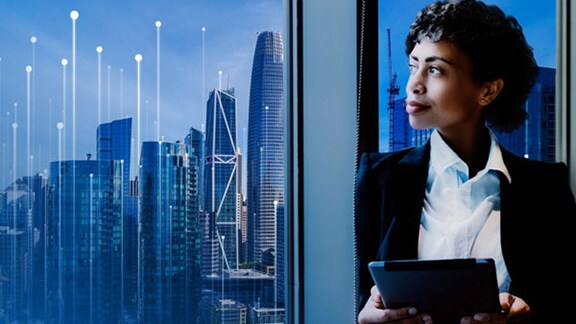 Businesswoman with a tab in hand looking out of an office window