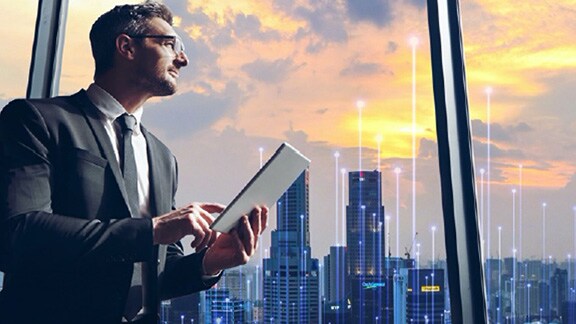 Businesswoman with a tab in hand looking out of an office window