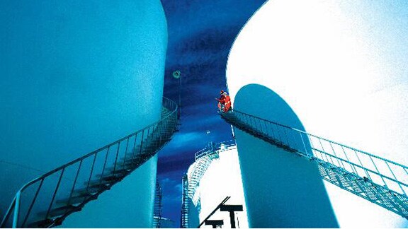 Two technicians inspecting the exterior of an oil tank