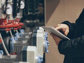 Close-up of a person working on a tablet and inspecting a fire suppression system