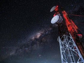 Satellite dishes against a star-lit sky at night