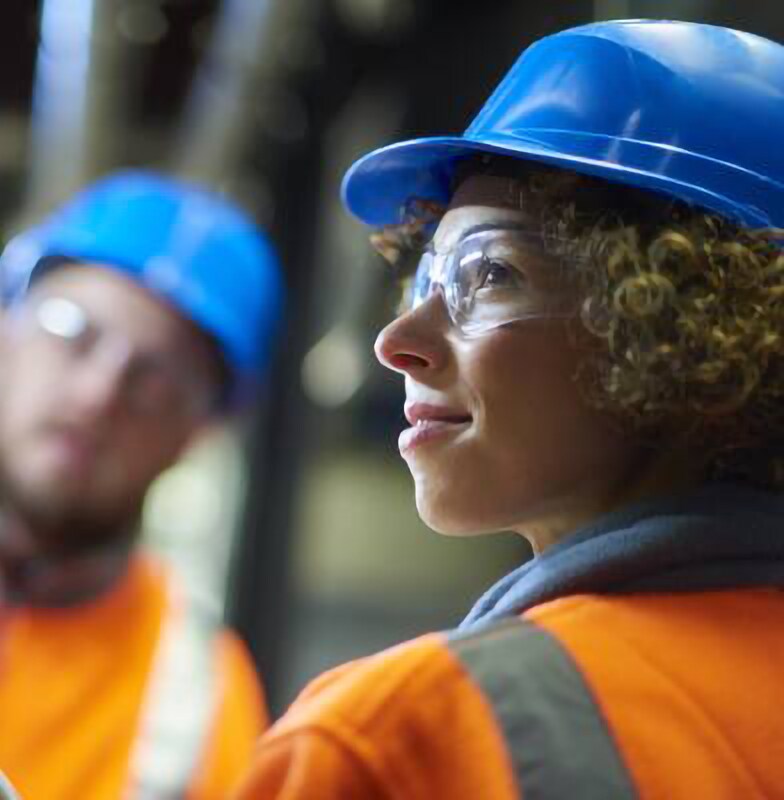 Two people wearing safety equipment working in a boiler room