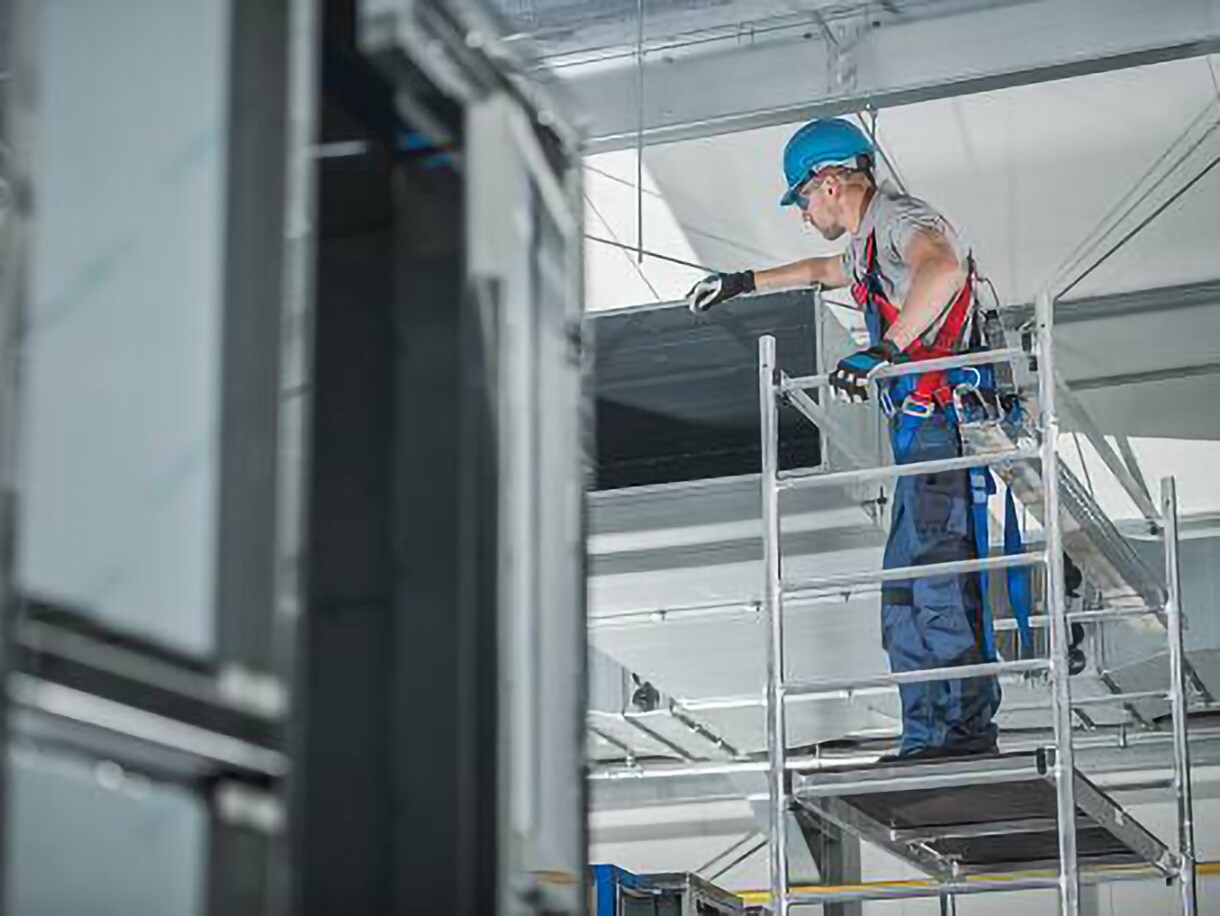 HVAC service worker in protective gear overseeing work in a facility