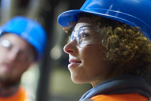 Two construction workers in protective glasses, clothing and helmet