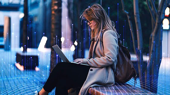 Woman sitting on a bench with a laptop in her lap