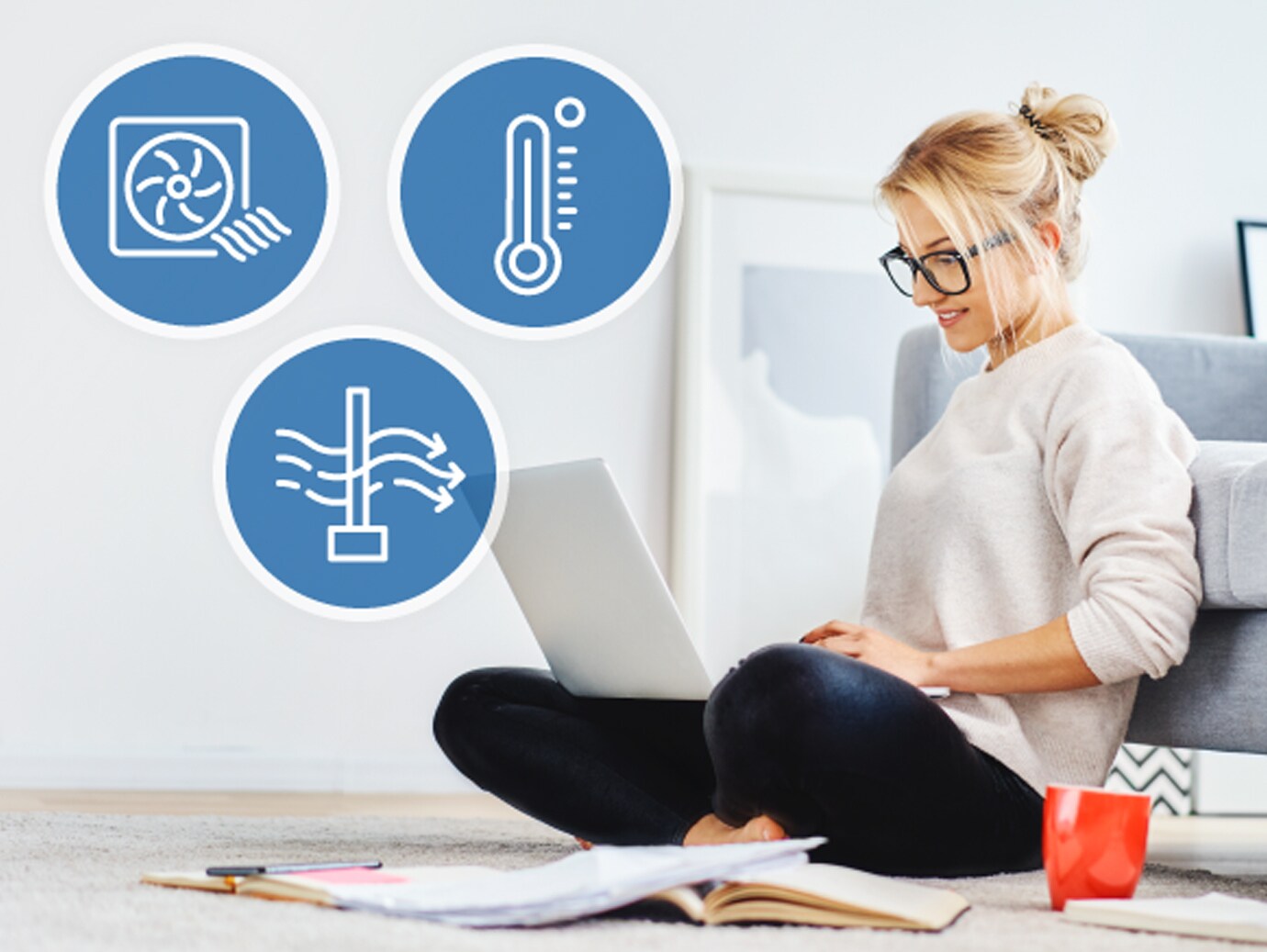 A woman seated beside a sofa and working on a laptop, with icons depicting features of networked thermostats overlaid on top
