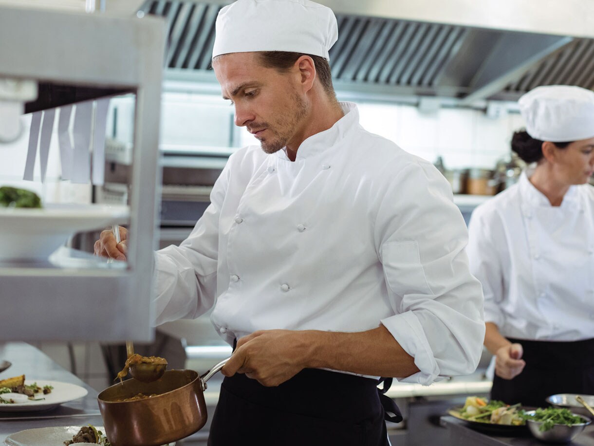 A chef holding a vessel in a kitchen