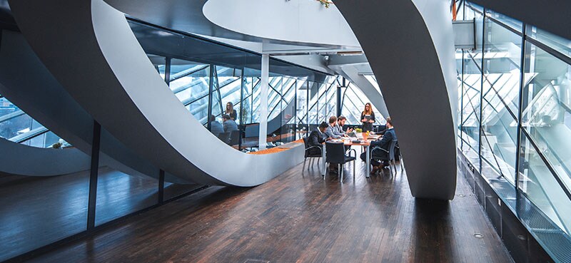 Interior of an office, where employees are seated a table in discussion.