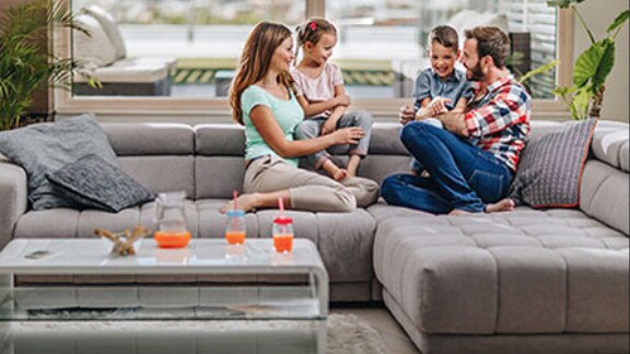 Family of four sitting on a sofa in their living room