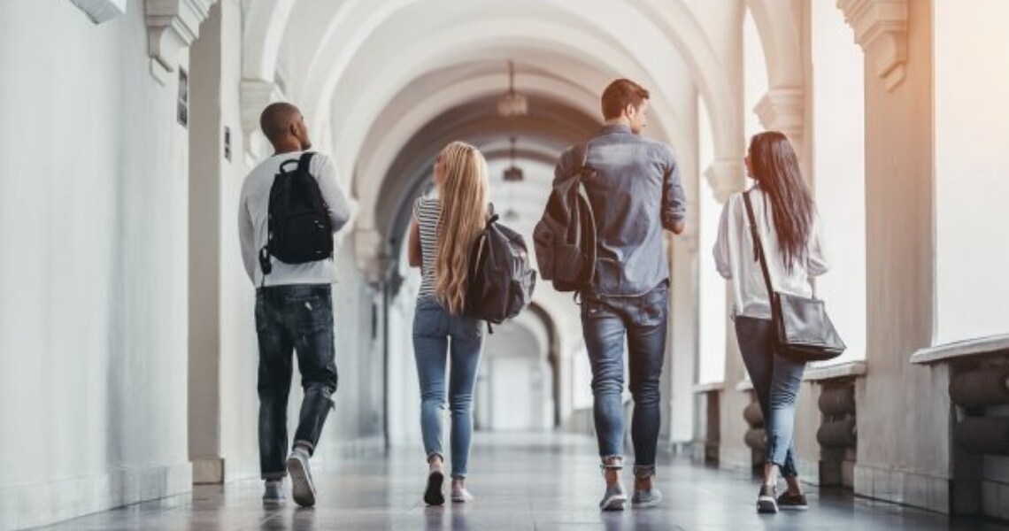 Rear view of university students walking along a hallway