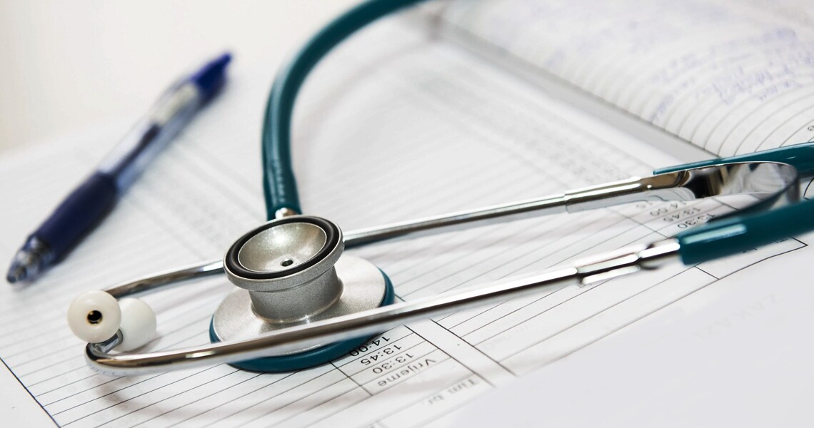 Close-up of a stethoscope and a pen on top of a medical report 