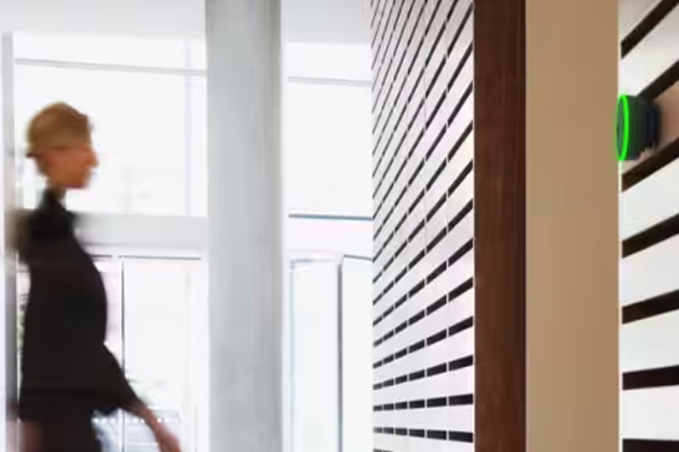Woman walking in an office room where the Tyco Illustra access management unit is in operation