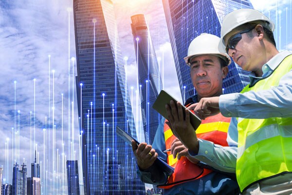 Two people using a tablet in front of a skyscraper with modern graphics