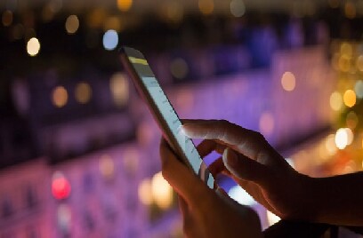 Close-up of a person's hand using a tablet on a balcony