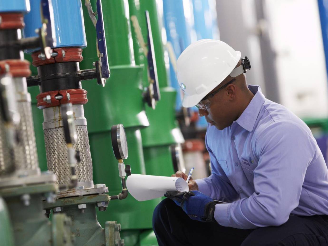A mechanic kneeling and taking readings for an HVAC device