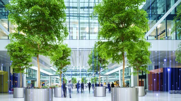 People walking in a large business atrium lined with trees