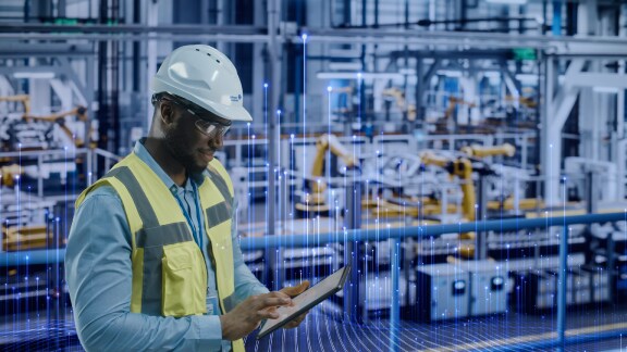 A maintenance worker scrolling on a tablet, with OpenBlue graphics in the background