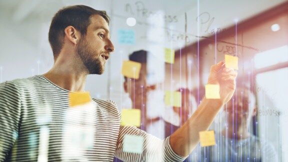 A man looking at a sticky note on a glass wall