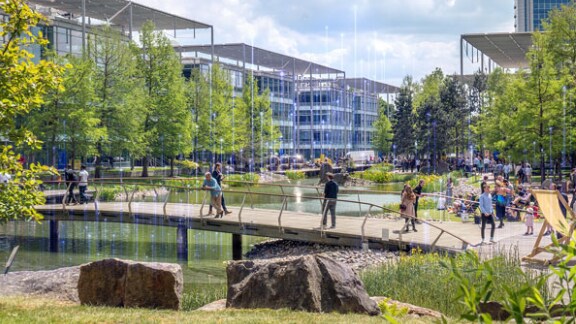 People walking along a bridge in a business park, with OpenBlue graphics overlaid in the background
