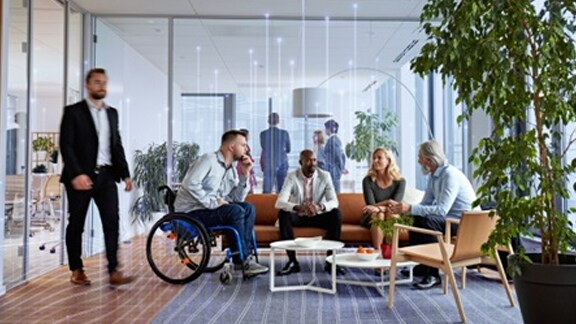 A group of employees sitting on a couch in an office and conversing