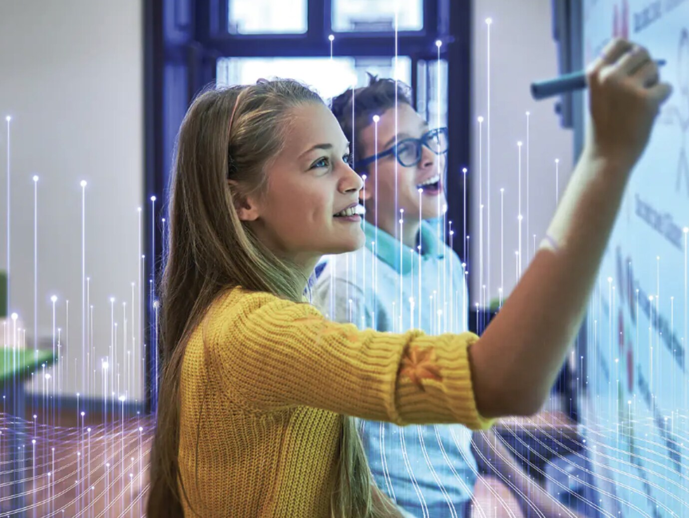 A girl writing on a whiteboard with a marker, while a boy in glasses smiles beside her
