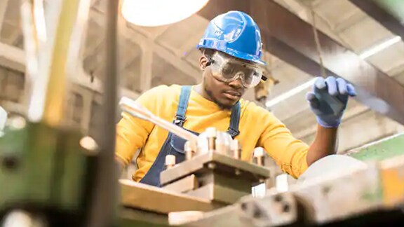 An engineer in protective gear working in a factory