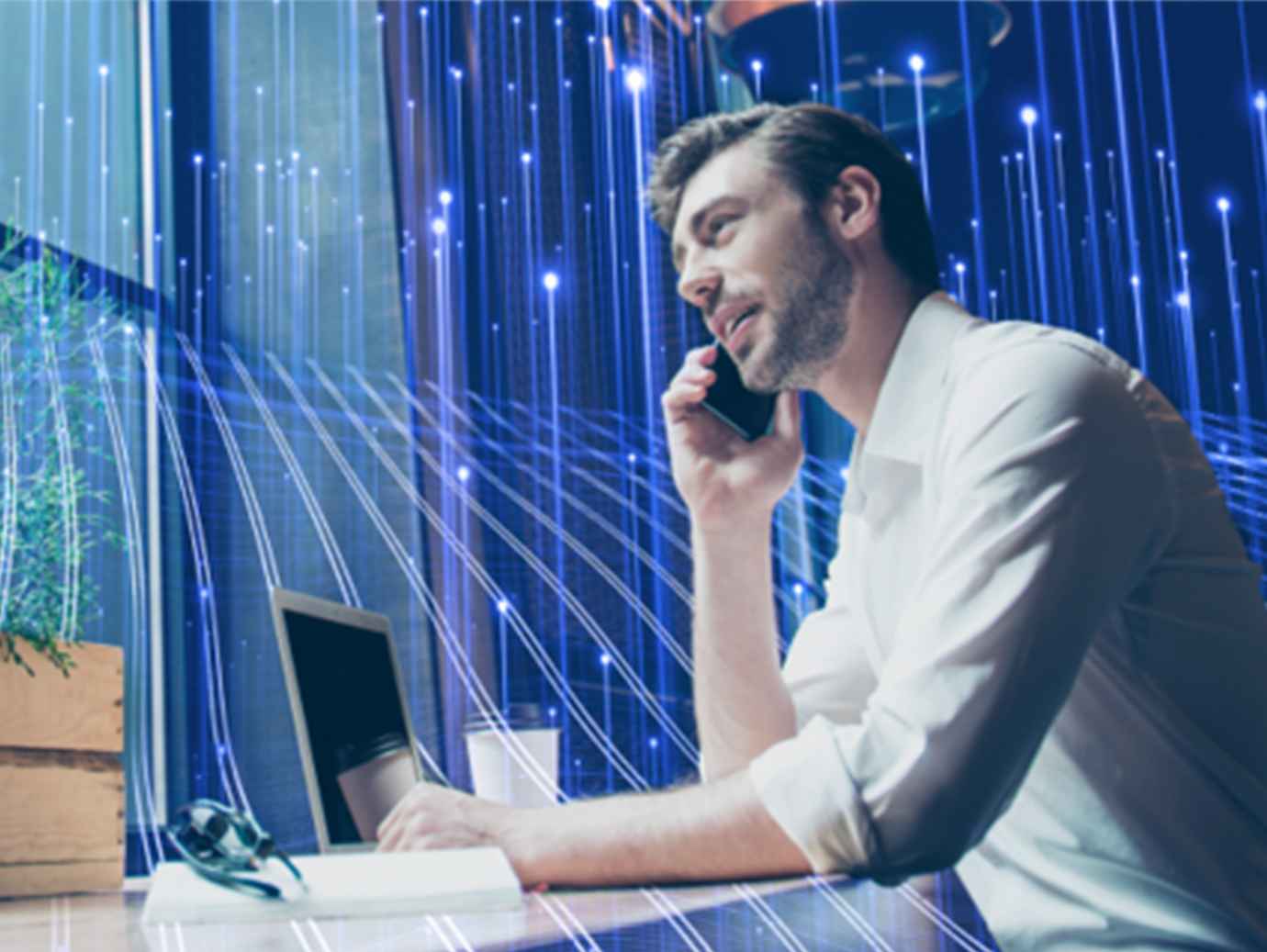 A man working on a laptop while talking on a mobile, overlaid with OpenBlue graphics