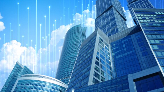 Skyscrapers with blue glass windows against a daytime sky, surrounded by OpenBlue graphics