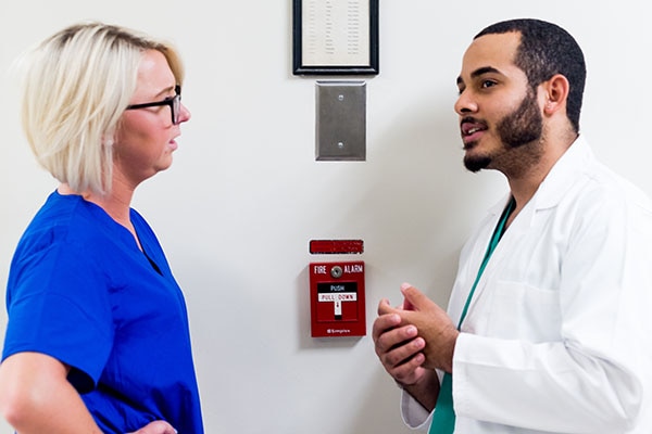 Two doctors talking next to an emergency fire alarm switch