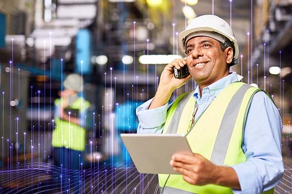 Maintenance worker holding a writing pad while talking on a mobile phone