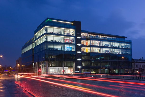 Exterior of an office building from the road at night with neon traffic lights