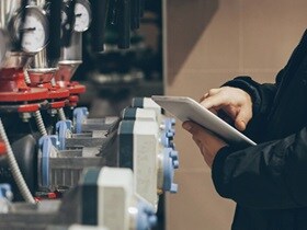 Close-up of a person working on a tablet and inspecting a fire suppression system